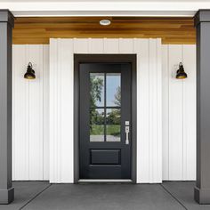 a black front door with two lamps on either side and one light hanging from the ceiling