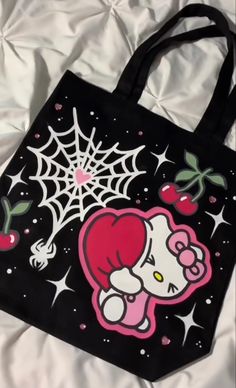 a hello kitty bag on a bed with white sheets and spider web in the background