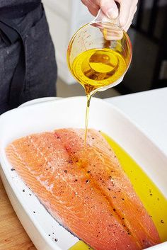 a person pouring oil on fish in a bowl