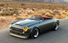 a green sports car is parked on the side of the road with mountains in the background