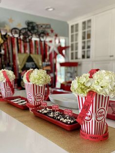 red and white striped popcorn buckets with flowers in them on a kitchen countertop