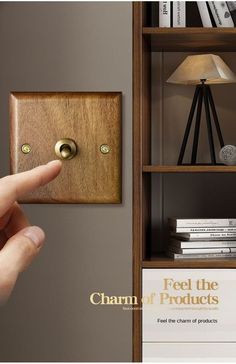 a hand is pointing at a light switch on the wall next to bookshelves