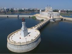 an aerial view of a lighthouse in the middle of a body of water near a bridge