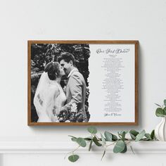 a framed wedding program is displayed on a mantle next to a potted plant and vase