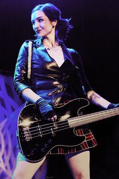 a woman holding a black bass guitar on stage