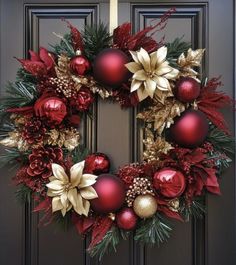 a christmas wreath with poinsettis and other decorations hanging on a front door