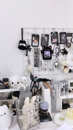 there are many stuffed animals hanging on the wall above the desk and behind it is a wire basket