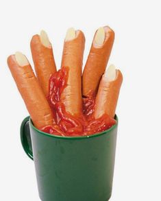 a green cup filled with hot dogs covered in ketchup