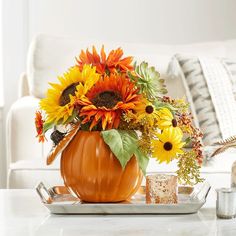 a pumpkin vase filled with sunflowers and other flowers