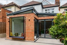 a brick building with an open patio and sliding glass doors on the outside, surrounded by greenery