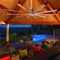 an outdoor dining area with tables and chairs under a wooden roof next to a swimming pool