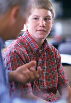 a young boy sitting next to an older man in a red and black checkered shirt