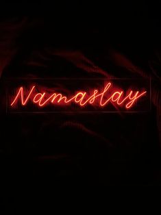 a neon sign that reads namastay in red on a black background with the word namastay lit up