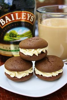 chocolate cookies with cream frosting on a white plate next to a bottle of bailey's