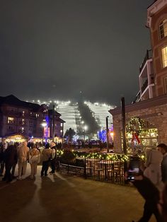 many people are walking around in the city at night with lights and decorations on them