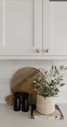 a potted plant sitting on top of a kitchen counter next to two black vases