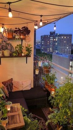 an apartment balcony with potted plants and lights on the roof terrace area, overlooking cityscape