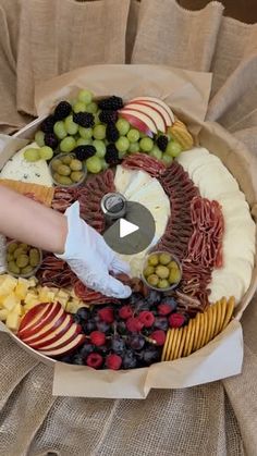 a platter filled with cheese, fruit and crackers on top of a table