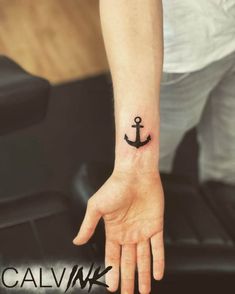 a small anchor tattoo on the left wrist and right hand is shown in black ink