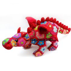 a red stuffed animal that looks like a dragon with flowers on it's body