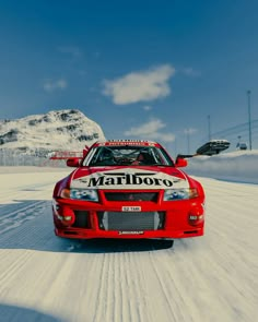 a red car driving down a snow covered road