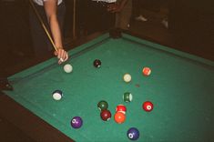 a man is playing pool on a green billiard's table with his friends