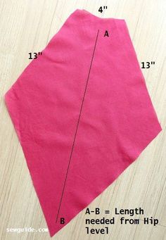 a pink piece of fabric with measurements for the top and bottom part, on a wooden surface