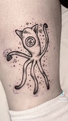 a black and white cat tattoo on the side of a woman's leg, with stars around it