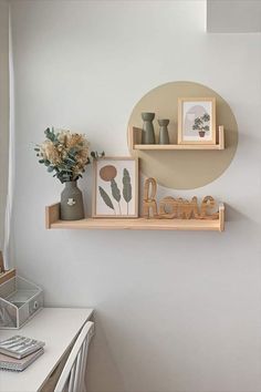 two wooden shelves with pictures and vases on them in front of a white wall