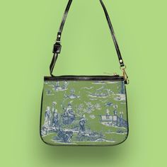 This unique and vibrant shoulder bag adds a chic touch to any outfit. Its compact size (10"w x 8"h) and lightweight construction makes it the perfect accessory for carrying around your essentials in style. A beautiful Cheng toile print in navy and green is printed onto high-grade vegan leather by our top-rated production partner, made to order just for you. .: 100% high-grade vegan leather .: Polyester lining + 20-inch black strap .: Two open pockets inside .: Gold-colored zipper and hardware .: Unique design only available here! Care instructions: avoid prolonged exposure to sunlight to ensure long lasting color rendering; store in a dry place; do not dry clean. Before cleaning the bag, remove all the items from the bag. Gently wipe surface with a soft cloth using mixture of mild laundry Vintage Coated Canvas Shoulder Bag For Evening, Rectangular Canvas Evening Bag, Vintage Canvas Shoulder Bag For Summer, Rectangular Canvas Bags For Evening, Summer Coated Canvas Shoulder Bag For Daily Use, Vintage Blue Canvas Shoulder Bag, Green Coated Canvas Shoulder Bag For On-the-go, Green Coated Canvas On-the-go Shoulder Bag, Rectangular Canvas Shoulder Bag With Zipper Pouch