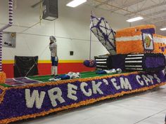 a man standing on top of a purple and orange float