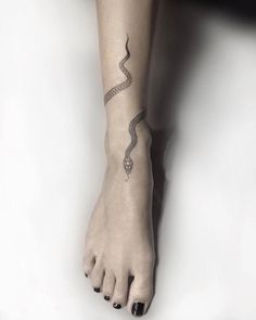 a woman's foot with a snake tattoo on her left leg and the bottom part of her arm