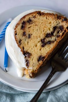 a piece of cake on a white plate with a blue striped fork next to it