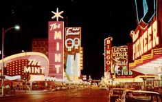 an old car is parked in front of the neon motels and casino signs at night