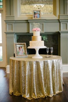 a table with a cake and wine glasses on it in front of a fire place