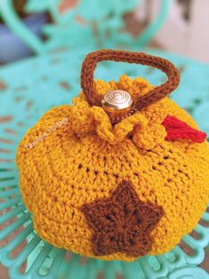 a crocheted yellow purse with a red and white button on the top sitting on a table