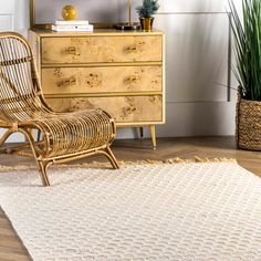 a wicker chair sitting on top of a wooden floor next to a dresser