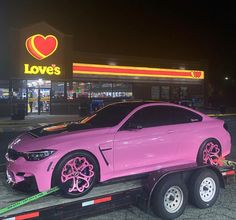 a pink car is being towed on a flatbed trailer in front of a love's store