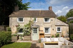 an old stone house with white furniture outside