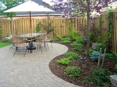 an outdoor patio with table, chairs and umbrellas in the middle of it's garden