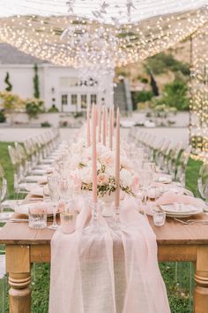 a table set up with candles, plates and napkins for a formal dinner party