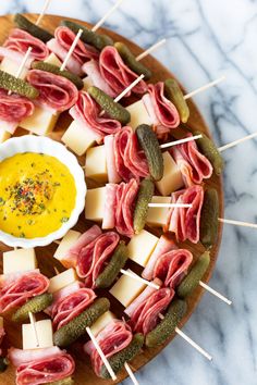 an assortment of appetizers with pickles and cheese on a wooden platter