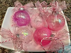 pink and silver christmas ornaments on a white plate with ribbon tied around the edges, sitting on a marble counter top