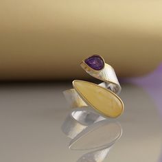 Modern amber ring This gold-plated silver ring features a beautiful amber stone. Every stone has its own unique pattern. It is a modern interpretation of a timeless classic. Modern gold plated silver ring with white amber and amethyst . The size is adjustable: size from 14 (7 US) up to 18 ( 8,5 US) Detals: handcrafted made out of sterling silver 925 gold plated. ring width about 7 mm dimensions of the amber 21 mm /9 mm weight [g]: 7,41 color of amber: unique butterscotch amber stone All Amber Ju Modern Amber Rings For Anniversary, Modern Amber Jewelry For Anniversary, Elegant Citrine Rings With Natural Stones, Modern Amber Gemstone Ring, Modern Amber Gemstone Jewelry, Modern Amber Jewelry With Citrine, Fine Jewelry Amber Ring With Polished Finish, Modern Amber Jewelry With Natural Stones, Fine Jewelry Amber Rings With Polished Finish