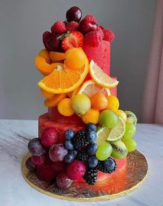 there is a cake made out of fruit on the plate and decorated with berries, oranges, raspberries, lemons, and strawberries