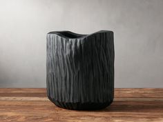 a black vase sitting on top of a wooden table