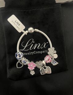 Linx smooth snake chain style charm bracelet in 925 sterling silver, with a ball clasp.  *Bracelet comes with 9 UNBRANDED charms in sterling silver with other alloy metals. *Additional charms may be added. *Compatible with all standard size open works charms. *Bracelet will also come in a velvet, jewelry pouch, making it perfect for gift giving also. *Please add 1 inch to the measurement of your wrist, in order to allow room for your charms, as charms will cause the bracelet to fit a bit tighter Metal Charm Bracelet With Lobster Clasp And Snake Chain, Metal Charm Bracelet With Snake Chain And Lobster Clasp, Metal Charm Bracelet With Snake Chain As Gift, Metal Snake Chain Charm Bracelet Gift, Sterling Silver Charms On Snake Chain, Sterling Silver Charms With Removable Snake Chain, Sterling Silver Charm Bracelet With Lobster Clasp Snake Chain, Snake Chain Charm Bracelet With Lobster Clasp For Gift, Silver Snake Chain Charms With Lobster Clasp