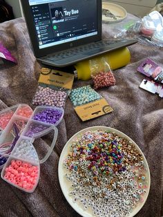 a laptop computer sitting on top of a table filled with lots of beads and candy