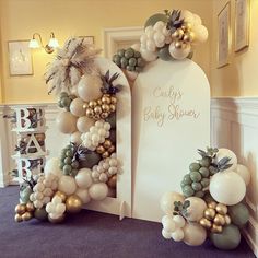 balloons and greenery decorate the entrance to a baby shower