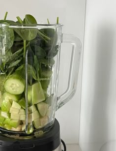 a blender filled with cucumbers and greens on top of a white counter